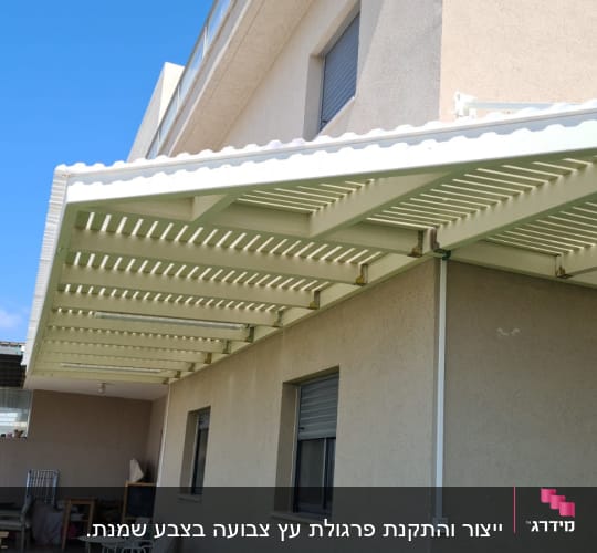 פרגולה לבנה מחוברת לקיר חיצוני של בית